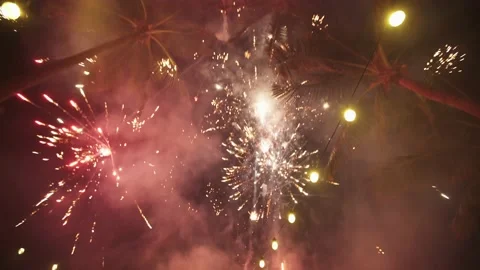 Fireworks explode at tropical resort very close to coconut trees. Video stock 135228720