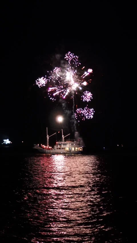 Fireworks Exploding Above Boat Reflecting on Water at Night Stock Footage 320228247