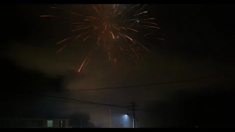 Fireworks exploding in night sky with smoke and power lines, no people Video stock 329773711