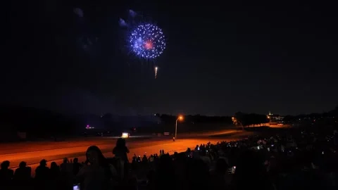Fireworks exploding over a crowd of spectators at night 動画素材 340942005
