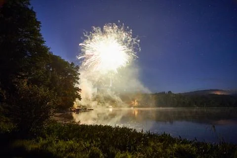 Fireworks exploding over lake at dusk Stock Photos
