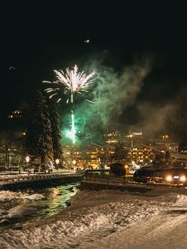 Fireworks exploding over snowy mountain village at night Stock Photos