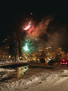 Fireworks exploding over snowy mountain village at night Stock Photos