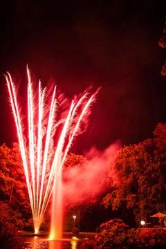 Fireworks Reflected In A Pond Surrounded By Trees Stock Photos