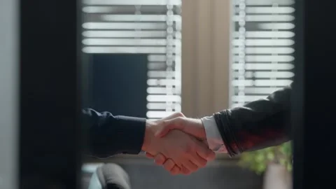 Firm handshake behind closed office doors, secrecy and tension. Legitimate Stock Footage 303582925