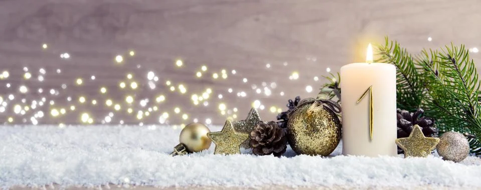 First Advent. Christmas background with Advent candle and golden decoration. Stock Photos