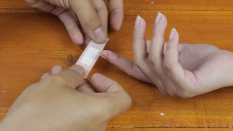 First aid for a hand bleeding from a knife with a bandage Stock Footage 263975072