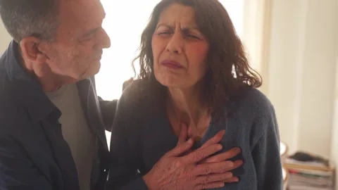 First aid in heart attack. Senior male helps female with chest pain Stock Footage 262982766