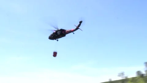 First Aid Helicopter Heading out and Dropping Water Over the Forest Stock Footage 130590199