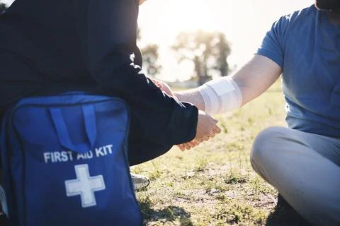 First aid, help and arm injury by man with medic on the ground during morning Stock Photos