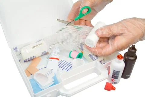 First aid kit and hands with gloves cutting the bandage Stock Photos