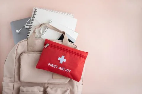 First aid kit on backpack with school supplies Stock Photos