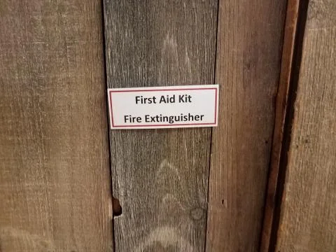First aid kit fire extinguisher sign on wood door Stock Photos