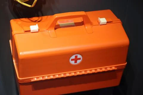 First aid kit, orange container with a cross. Portable basic first aid equipm Stock Photos