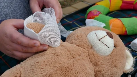 First aid to teddy bear by small child giving bandage 库存影片 103095608