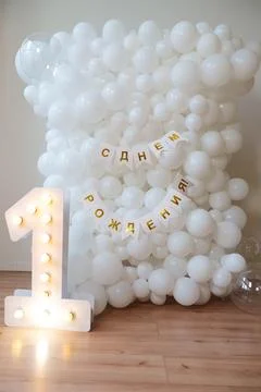 First birthday white balloon backdrop with lighted number one Stock Photos