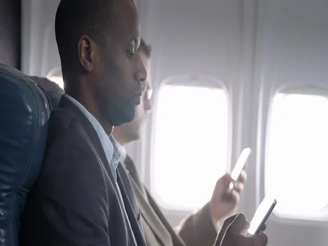 First class airline passengers using mobile devices on commercial flight 4K Stock Footage 69805473