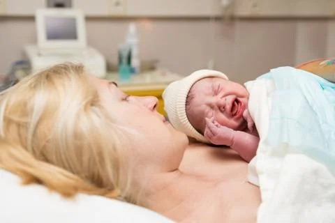 First cry of a newborn baby. Skin to the skin with mother Stock Photos