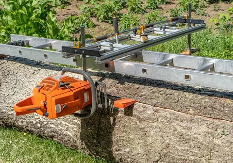 The first cut is made for the spruce log with a mobile chainsaw mill. Stock Photos