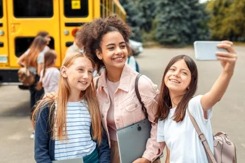 First Day. Classmates going to school by bus girls standing close-up hugging Foto stock