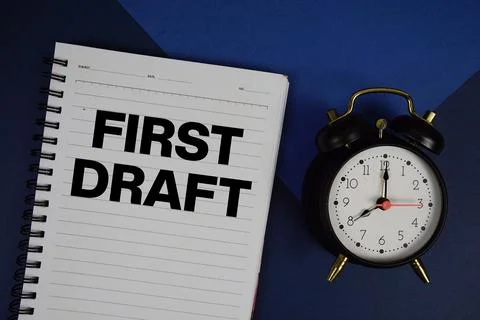 First Draft text written on notepad with alarm clock on navy blue background Stock Photos