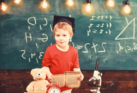 First former interested in studying, education. Kid boy in graduate cap holds Stock Photos