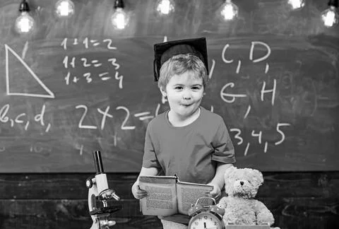 First former interested in studying, education. Kid boy in graduate cap holds Stock Photos