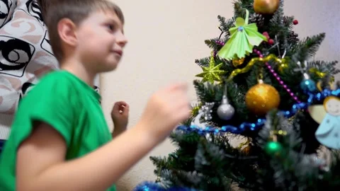 A first-grade boy and his mother decorate an artificial Christmas tree at home Stock Footage 323082204