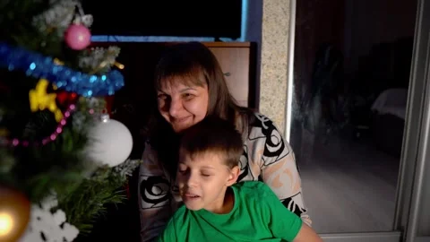 A first-grade boy and his mother decorate an artificial Christmas tree at home Stock Footage 323702056