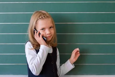 A first grade student at school speaks by phone. emotions of schoolgirls Stock Photos