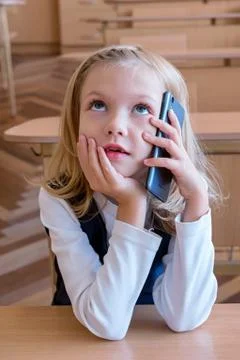 A first grade student at school speaks by phone. emotions of schoolgirls Stock Photos