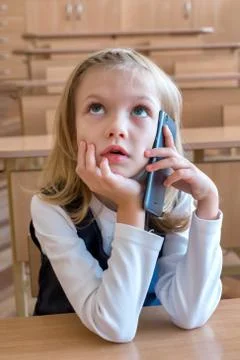 A first grade student at school speaks by phone. emotions of schoolgirls Stock Photos
