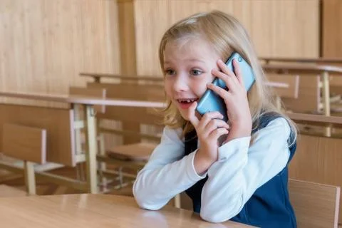 A first grade student at school speaks by phone. emotions of schoolgirls Stock Photos