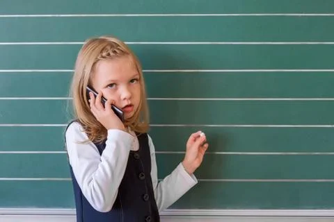 A first grade student at school speaks by phone. emotions of schoolgirls Stock Photos