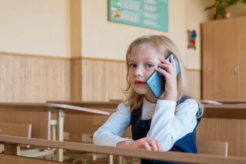 A first grade student at school speaks by phone. emotions of schoolgirls Stock Photos