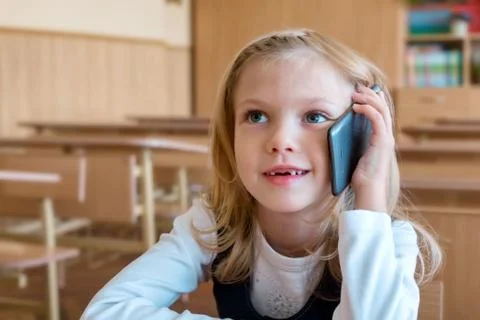 A first grade student at school speaks by phone. emotions of schoolgirls Stock Photos