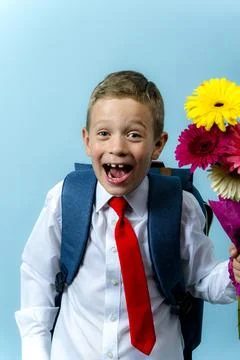 First grader with a backpack holds a bouquet of flowers in his hands Foto stock