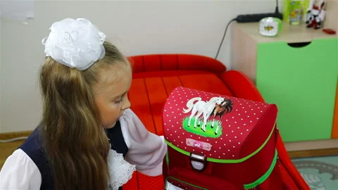 First-grader checks the completeness of her backpack in front of the school Stock Footage 102739542
