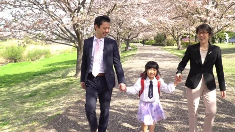 A First Grader Girl Walking Hand in Hand with Her Parents Stock Footage 331979764