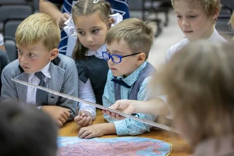 A first grader with glasses examines a map in the lesson. September 1. School. Stock Photos