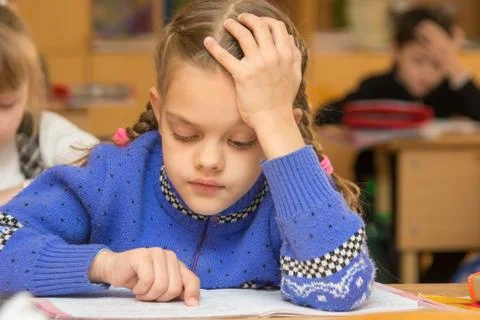 First-grader at a lesson reads the text, running his finger along the lines Stock Photos