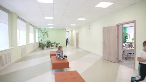 First-grader sits quietly in bright wide school corridor Stock Footage 310243233