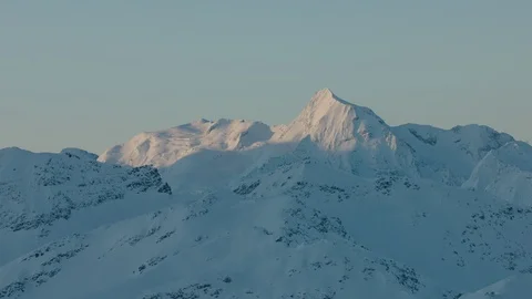 The first light shines on a snow covered mountain in the distance Stock Footage 102183802