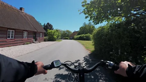 First-person chest-mounted view riding an electric bike along a paved road past Stock Footage 345625463