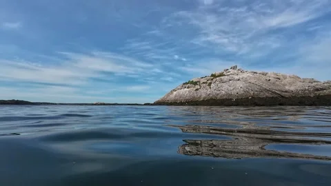 First-Person Coastal View of a Quiet Rocky Island and Rolling Blue Ocean Waves Video stock 344763844
