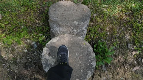 First person downward view of walking on stone columns across garden pond, 4K Stock Footage 106949326