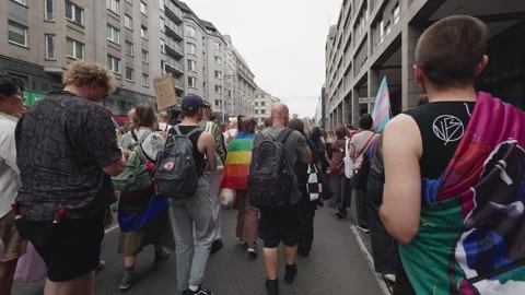 First-person follow of a small group with Pride flags draped over their Stock Footage 346239367