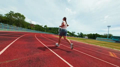 First Person FPV Drone Chasing a Woman Running Around a Stadium Track, Ultra Low Stock Footage 338188615