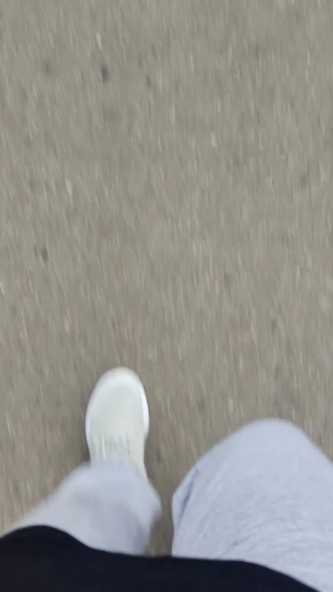 First-person motion blur POV of white sneakers walking on asphalt Stock Footage 336732482