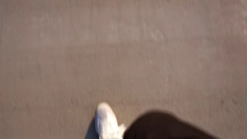 First-Person Perspective of Walking on a Concrete Sidewalk with White Sneakers Stock Footage 301490319
